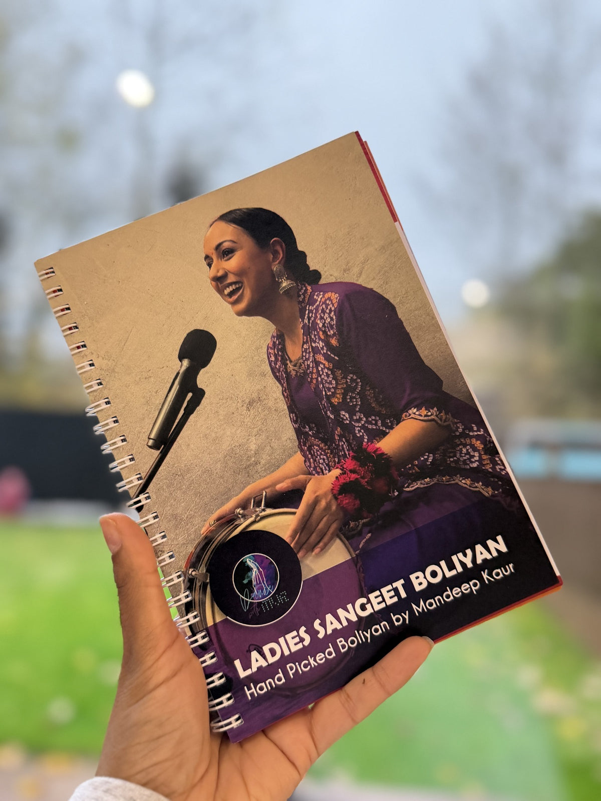 Ladies Sangeet Boliyan book by Mandeep Kaur displayed in hand, featuring Punjabi songs for wedding celebrations.
